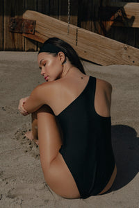 THE TOBI MAILLOT BLACK ONE PIECE SWIMSUIT ONE SHOULDER BATHING SUIT WITH GOLD PEARL BROOCH SUSTAINABLE BATHING SUIT LUXURY DESIGNER SWIMWEAR